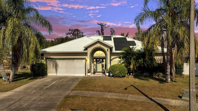 view of front of home with a garage, a yard, and solar panels