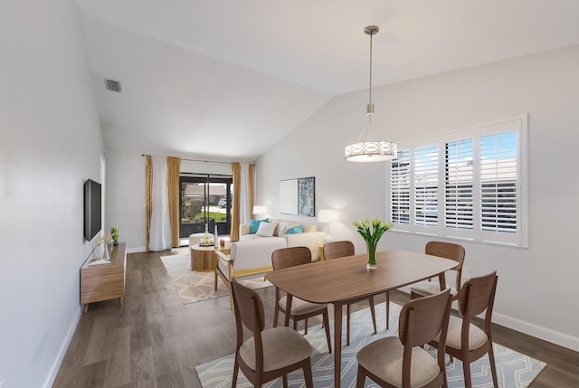 dining space with dark wood-type flooring and high vaulted ceiling