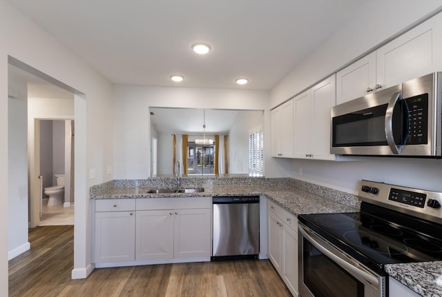 kitchen featuring sink, white cabinetry, a chandelier, appliances with stainless steel finishes, and pendant lighting