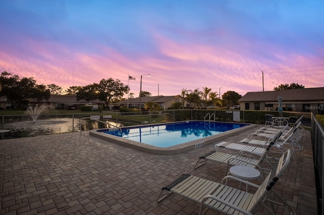 pool at dusk with a patio area