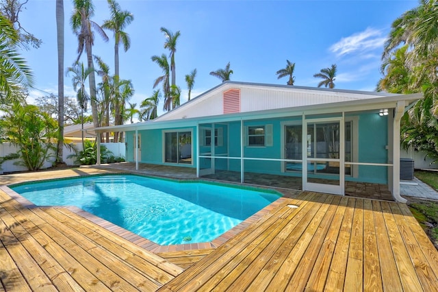 pool featuring a sunroom, fence, and a wooden deck