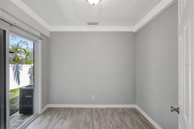 empty room with light wood-style floors, visible vents, and baseboards