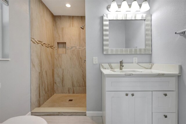 full bathroom featuring toilet, tiled shower, and vanity