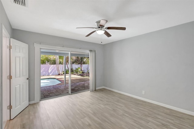 spare room with light wood finished floors, baseboards, visible vents, and ceiling fan