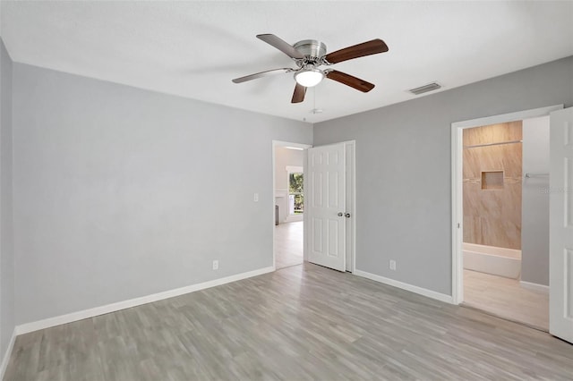 unfurnished bedroom with visible vents, ceiling fan, ensuite bath, wood finished floors, and baseboards