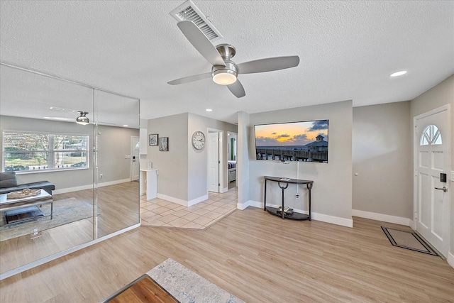 foyer entrance featuring ceiling fan, a textured ceiling, and light wood-type flooring