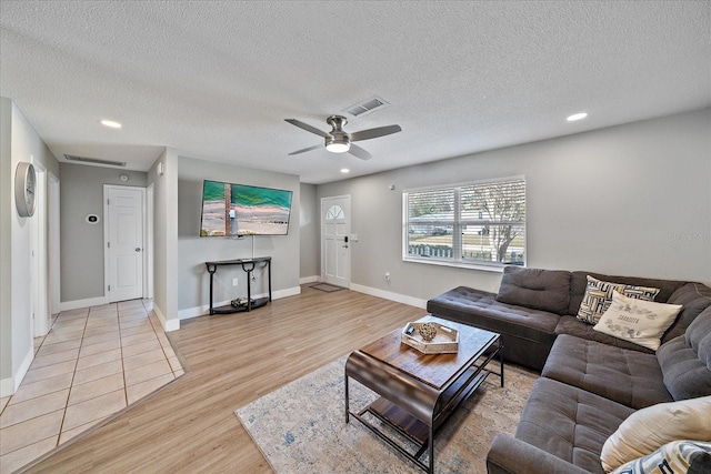 living room with a textured ceiling, ceiling fan, and light hardwood / wood-style flooring