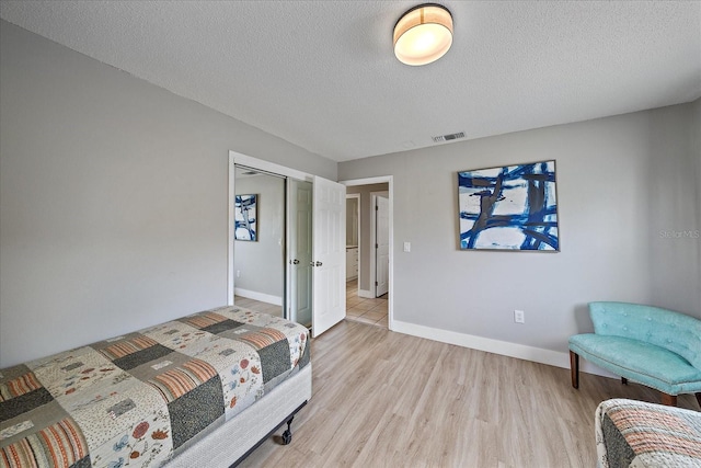 bedroom featuring a closet, light hardwood / wood-style flooring, and a textured ceiling