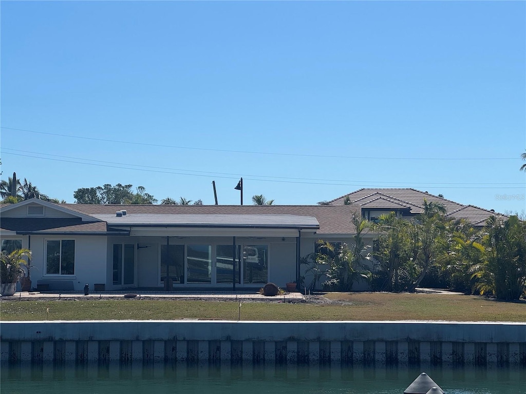 rear view of property featuring a water view and a yard
