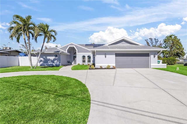 single story home with a garage, a front lawn, and solar panels