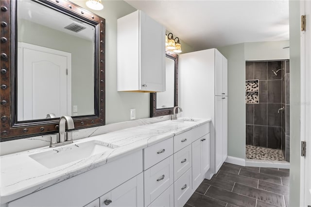 bathroom featuring tiled shower and vanity