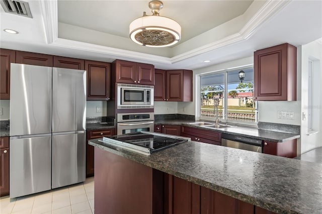 kitchen featuring a sink, a raised ceiling, reddish brown cabinets, and appliances with stainless steel finishes