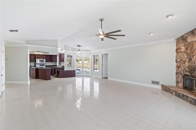 living room featuring visible vents, baseboards, a stone fireplace, and ceiling fan