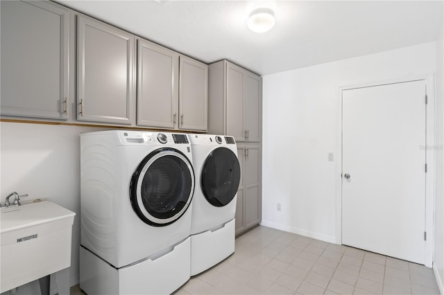 laundry area featuring a sink, baseboards, cabinet space, and independent washer and dryer