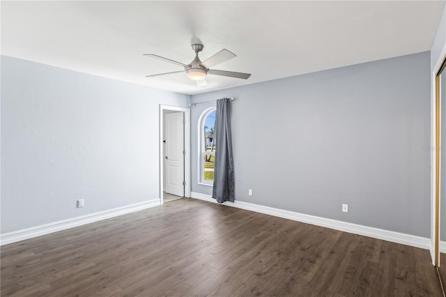 unfurnished room featuring dark wood-style floors, ceiling fan, and baseboards