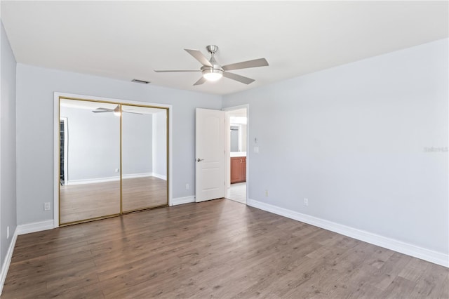 unfurnished bedroom with a ceiling fan, wood finished floors, visible vents, baseboards, and a closet