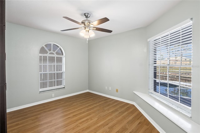 unfurnished room featuring a ceiling fan, wood finished floors, and baseboards