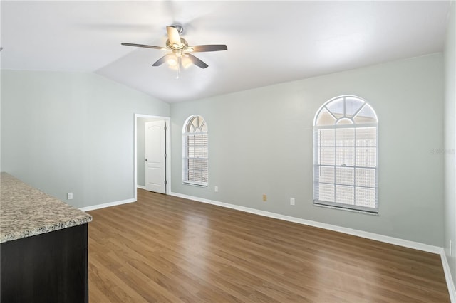 unfurnished living room featuring vaulted ceiling, wood finished floors, baseboards, and ceiling fan