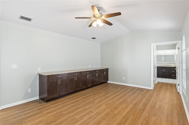 spare room with vaulted ceiling, baseboards, visible vents, and light wood finished floors