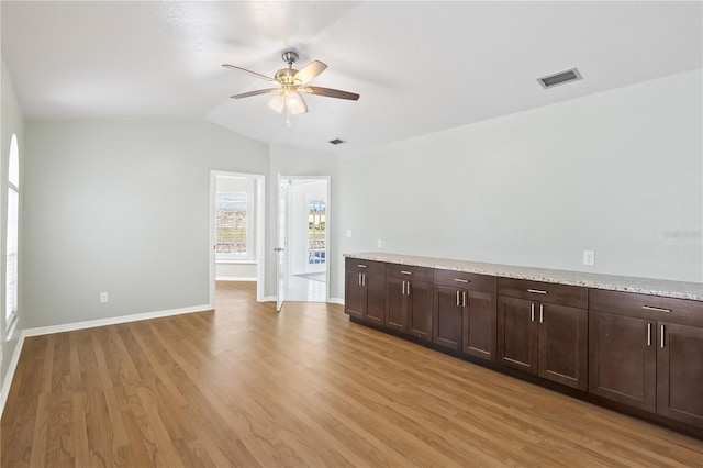 spare room with visible vents, baseboards, ceiling fan, lofted ceiling, and light wood-style flooring