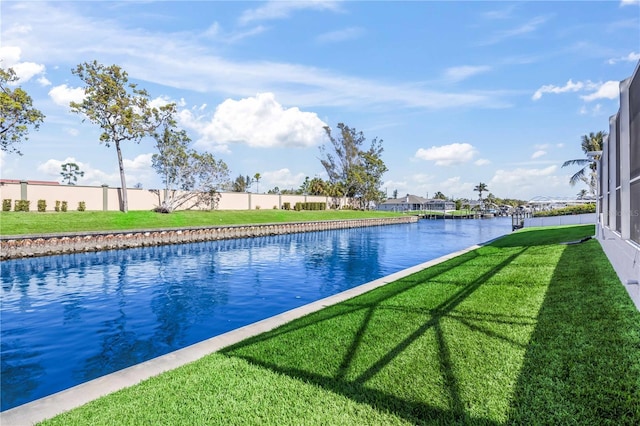 view of pool with a lawn, fence, and a water view