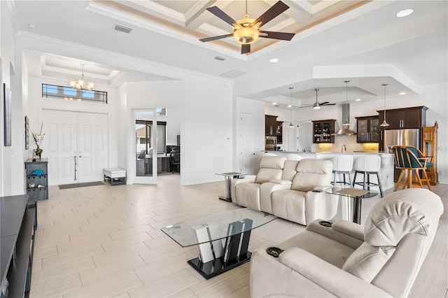 living room featuring coffered ceiling, crown molding, a tray ceiling, a towering ceiling, and ceiling fan with notable chandelier