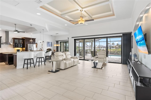 living room featuring coffered ceiling, crown molding, ceiling fan, and a high ceiling