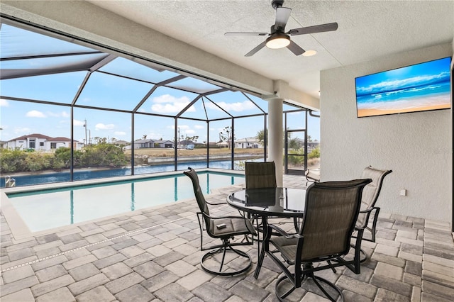 view of patio / terrace featuring a water view, ceiling fan, and glass enclosure