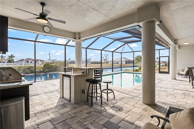 view of swimming pool featuring a lanai, ceiling fan, a patio area, area for grilling, and exterior bar