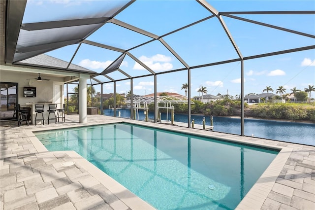 view of pool with a lanai, an outdoor bar, ceiling fan, a water view, and a patio area