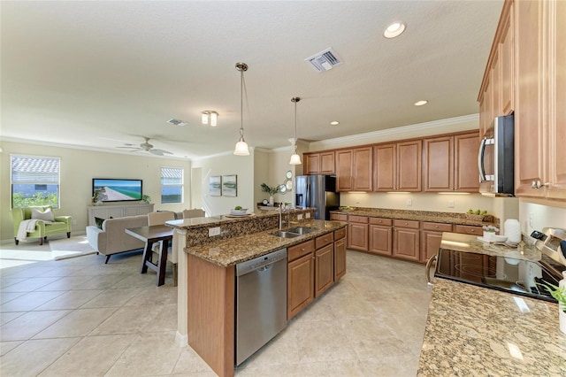 kitchen with sink, light stone counters, decorative light fixtures, appliances with stainless steel finishes, and an island with sink