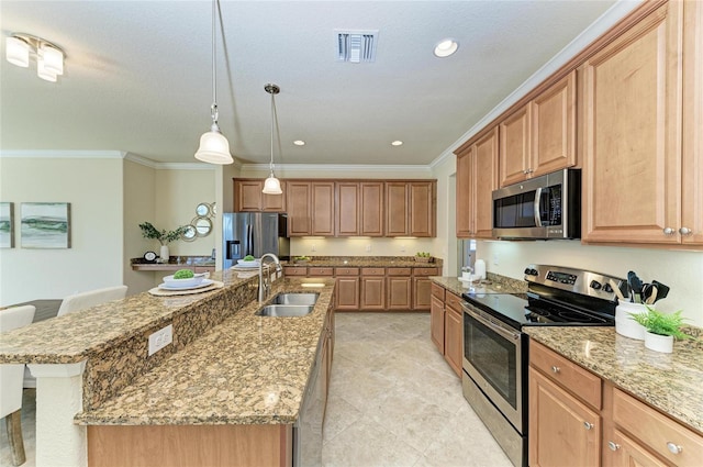 kitchen featuring sink, a kitchen breakfast bar, hanging light fixtures, stainless steel appliances, and a center island with sink