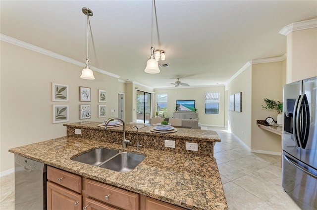 kitchen with sink, a center island with sink, stainless steel appliances, ornamental molding, and stone countertops