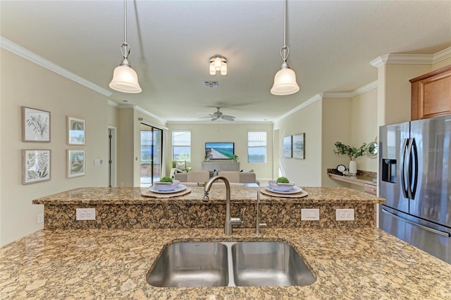 kitchen with sink, light stone counters, stainless steel fridge with ice dispenser, ornamental molding, and pendant lighting