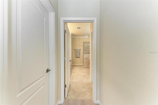 hallway with crown molding and light tile patterned floors