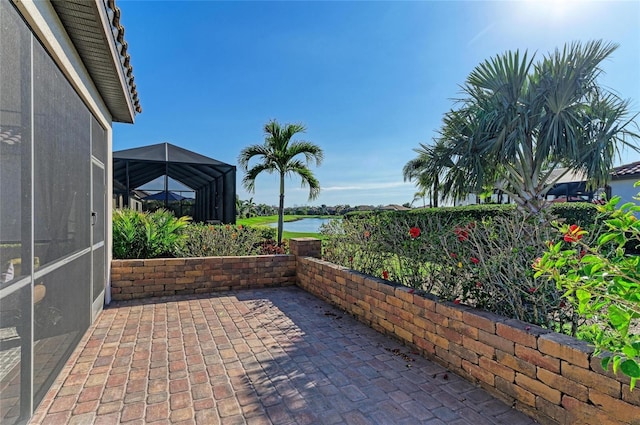 view of patio featuring a water view and glass enclosure