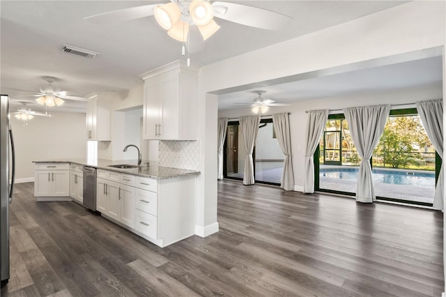 kitchen with stainless steel appliances, a sink, visible vents, white cabinets, and decorative backsplash