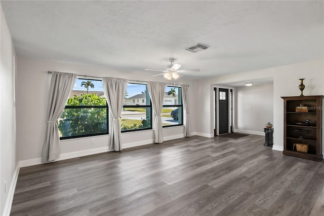 unfurnished living room featuring visible vents, dark wood-type flooring, ceiling fan, a textured ceiling, and baseboards