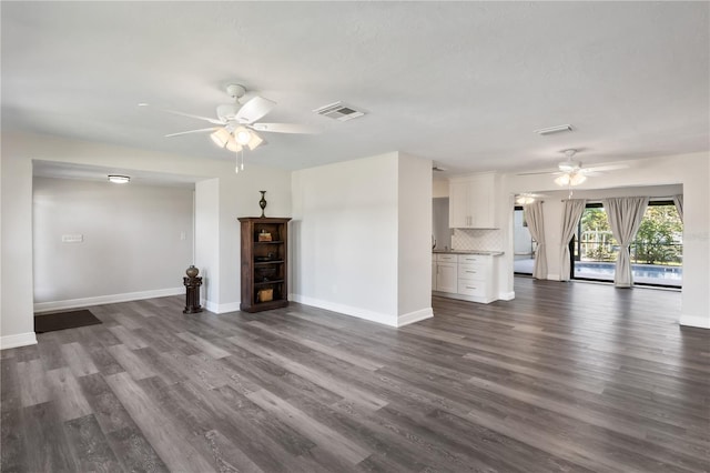 unfurnished living room featuring ceiling fan, dark wood finished floors, visible vents, and baseboards