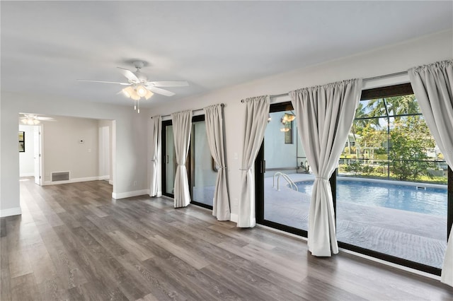 unfurnished room with a ceiling fan, baseboards, visible vents, and wood finished floors