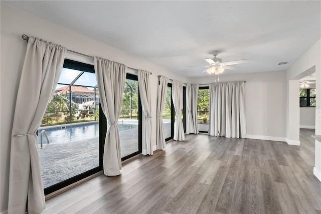 interior space with a sunroom, baseboards, visible vents, and wood finished floors