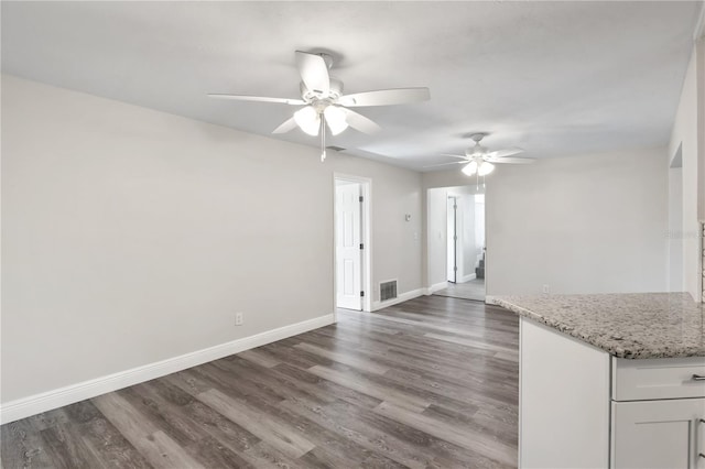 interior space featuring a ceiling fan, baseboards, visible vents, and dark wood-type flooring