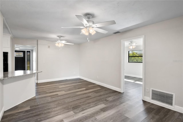 spare room with baseboards, visible vents, and dark wood-style flooring