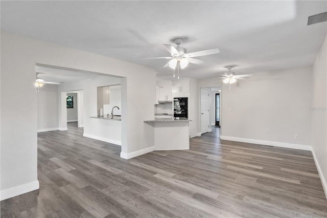 unfurnished living room featuring dark wood-style flooring, a sink, visible vents, and baseboards