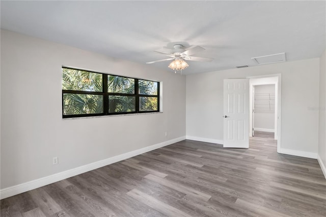 unfurnished room with visible vents, dark wood-style flooring, attic access, and baseboards