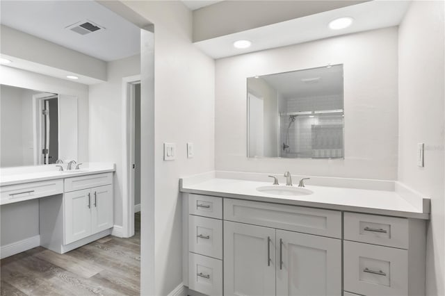 bathroom featuring visible vents, vanity, a shower stall, wood finished floors, and baseboards