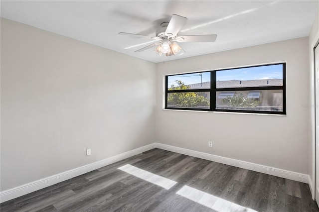 spare room featuring dark wood-style floors, ceiling fan, and baseboards