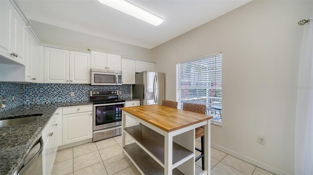 7632 Plantation Cir, Bradenton, FL 34201 - kitchen featuring butcher block counters, light tile patterned floors, tasteful backsplash, and appliances with stainless steel finishes