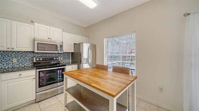 7632 Plantation Cir, Bradenton, FL 34201 - kitchen with light tile patterned floors, stainless steel appliances, tasteful backsplash, white cabinets, and baseboards