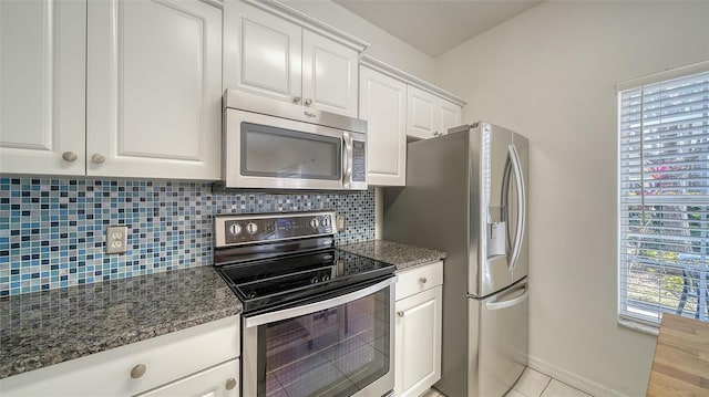 7632 Plantation Cir, Bradenton, FL 34201 - kitchen with light tile patterned floors, tasteful backsplash, white cabinets, dark stone counters, and appliances with stainless steel finishes